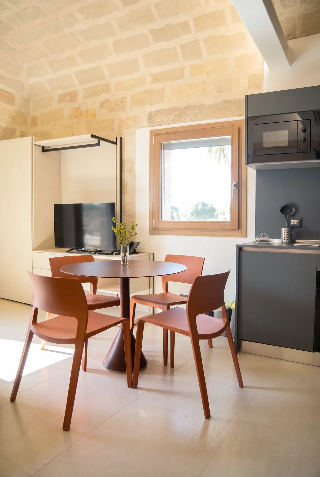 La zona giorno di Pirreca, il tavolo tondo con le sedie terracotta sotto la volta di calcarenite, accanto alla cucina