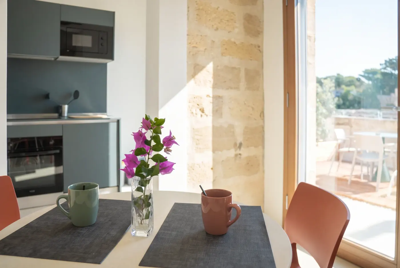 The kitchenette at Cala Grande and the laid table in front of the window onto the outdoor space
