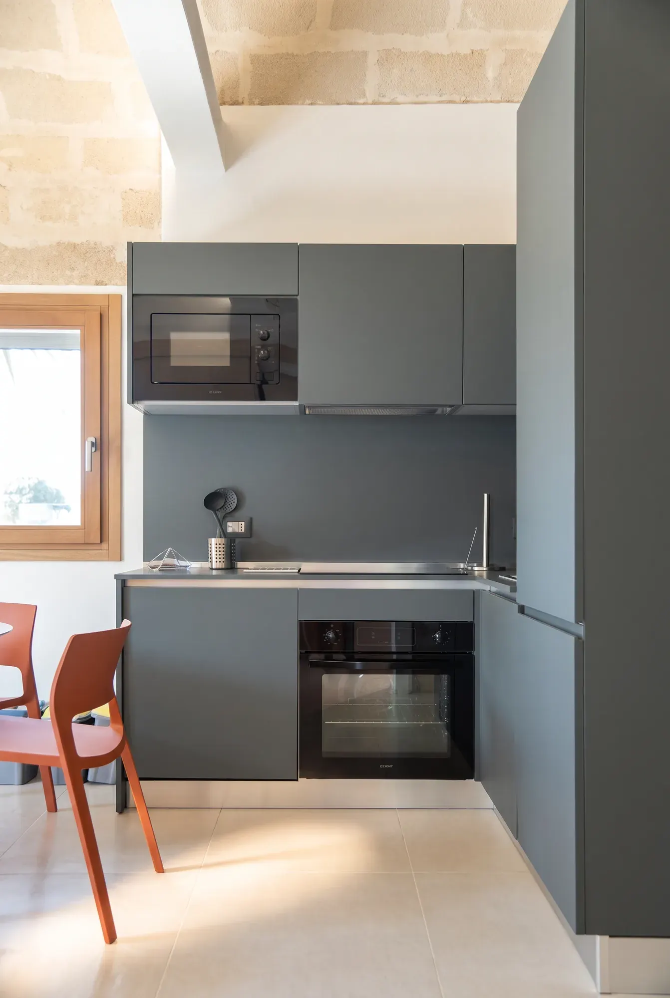 La cucina di Pirreca, il blocco grigio con forno e microonde sotto la volta di calcarenite