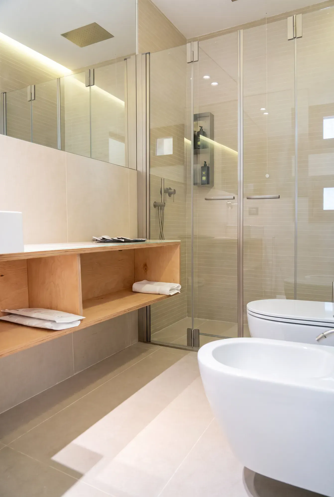 The bathroom at Cala Grande, glass-walled shower and stone shelf