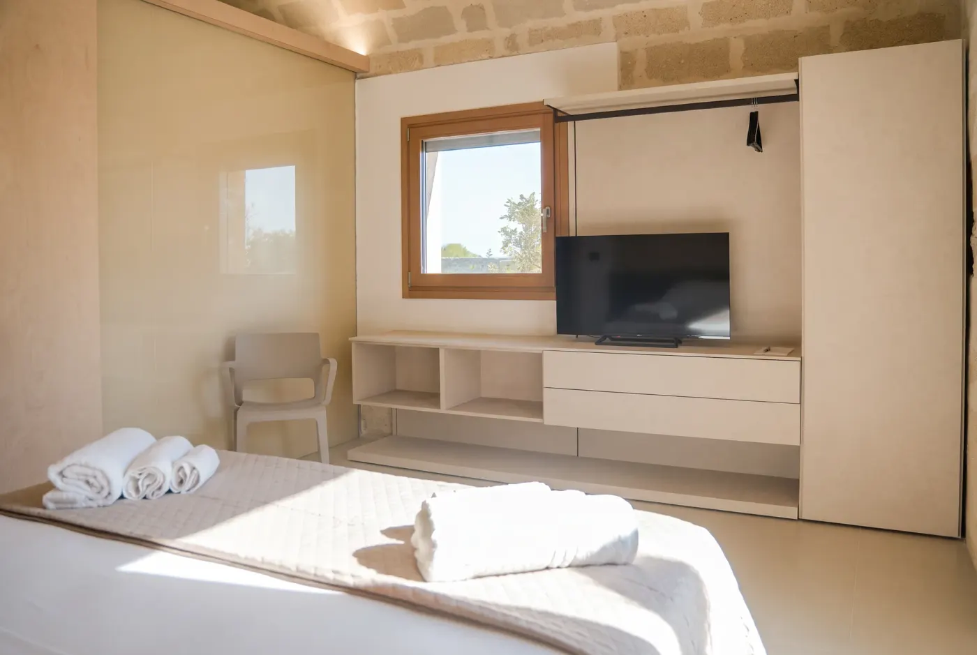 La camera di Pirreca vista dal letto, il mobile chiaro e la finestra sul verde
