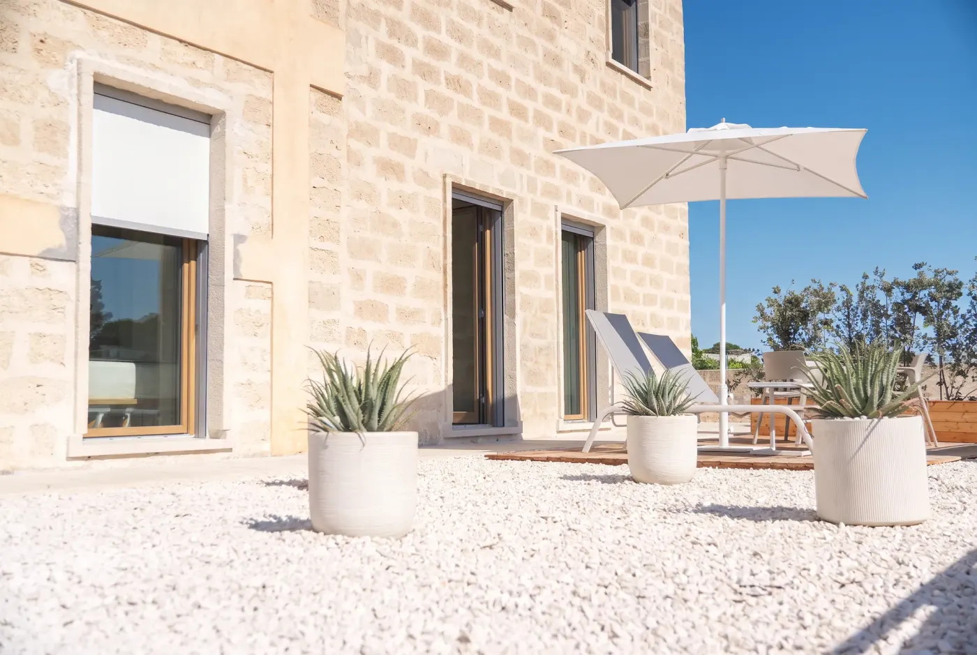 The calcarenite block facade at Cala Grande, the loungers and pots on the white gravel