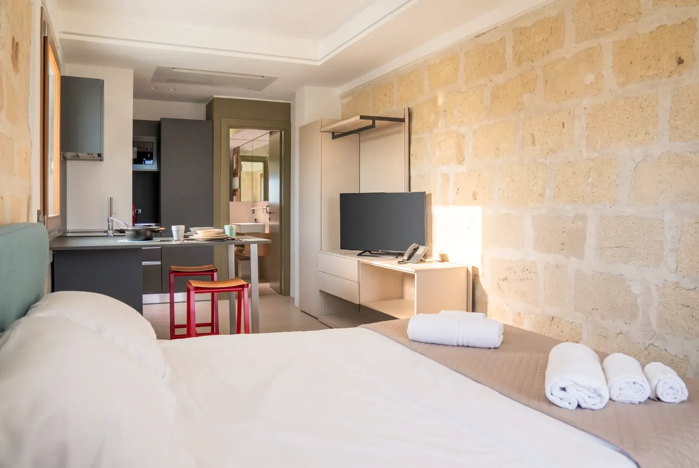 Il letto e, di fronte, il televisore e la cucina