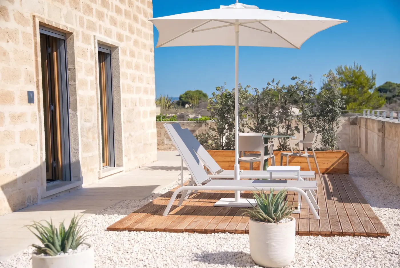 The outdoor space at Cala Grande, parasol and loungers on the wooden deck
