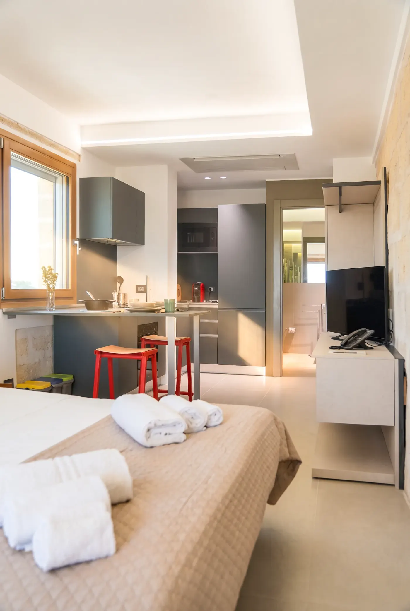 Il letto in primo piano, la cucina e la porta del bagno sul fondo