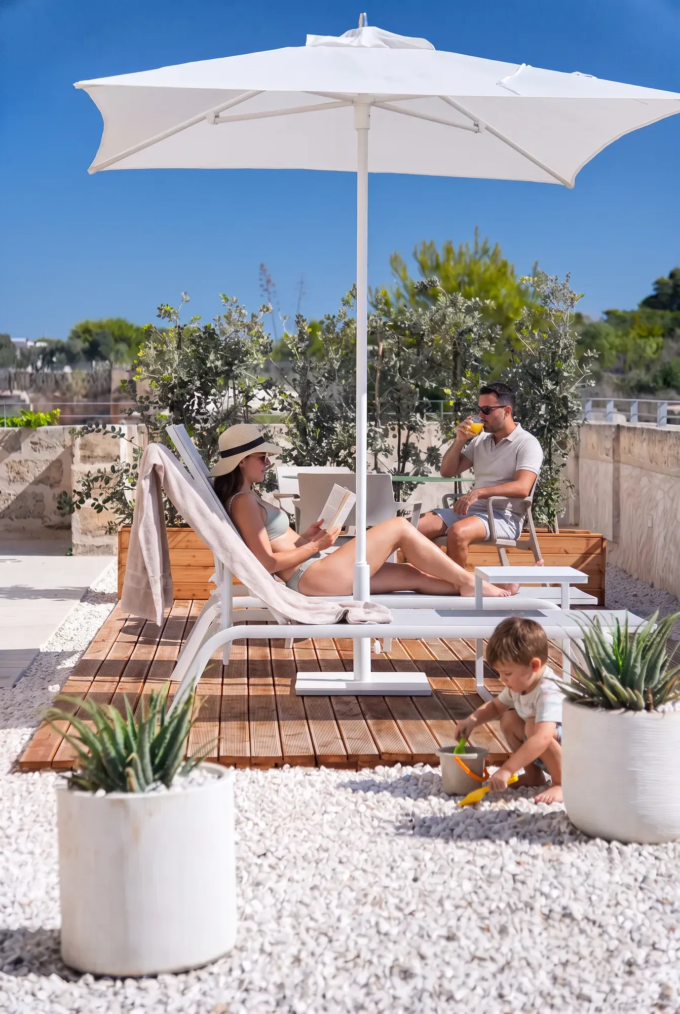 A family on the deck at Cala Grande, reading in the shade of the parasol
