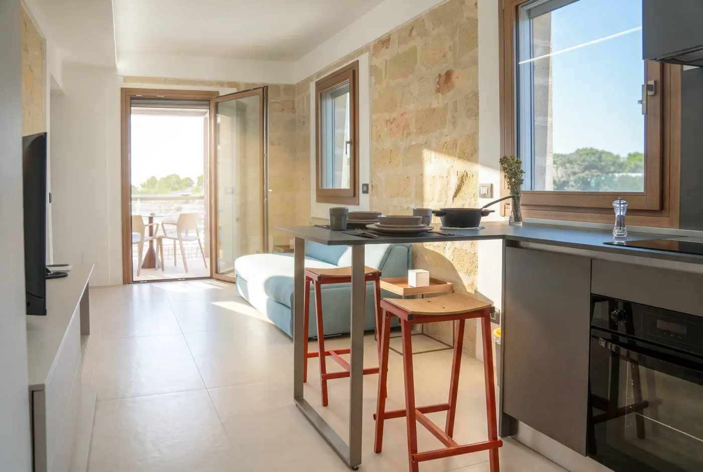 Il letto accanto alla finestra e la cucina sullo sfondo