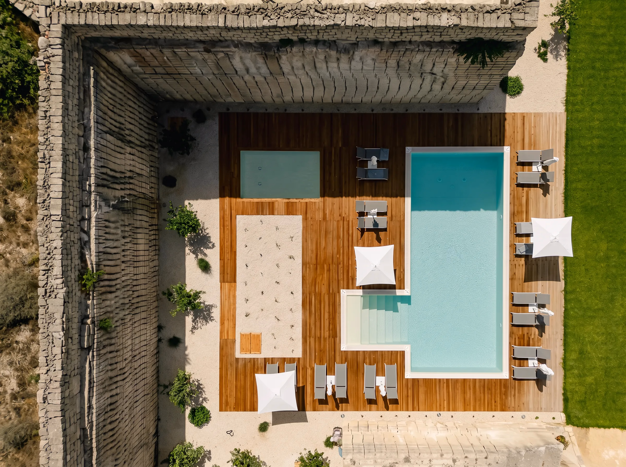 Vista perfettamente zenitale della piscina e del deck, racchiusi dal muro a secco