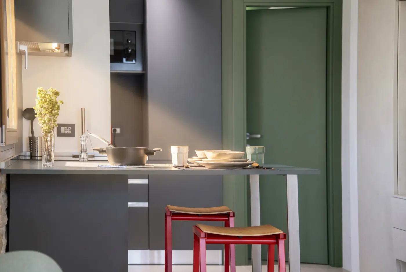 La cucina con il piano cottura e la porta verde del ripostiglio