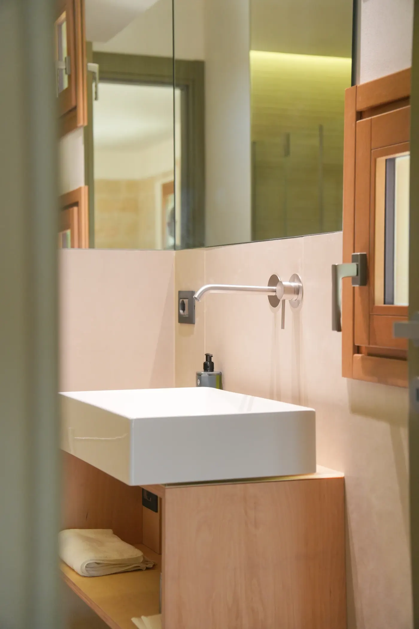 Il lavabo in appoggio sul mobile in legno chiaro, con il sapone