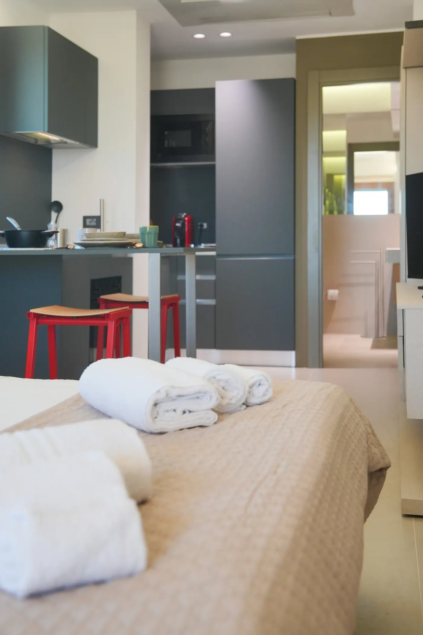 Il letto e, alle spalle, la cucina con gli sgabelli rossi
