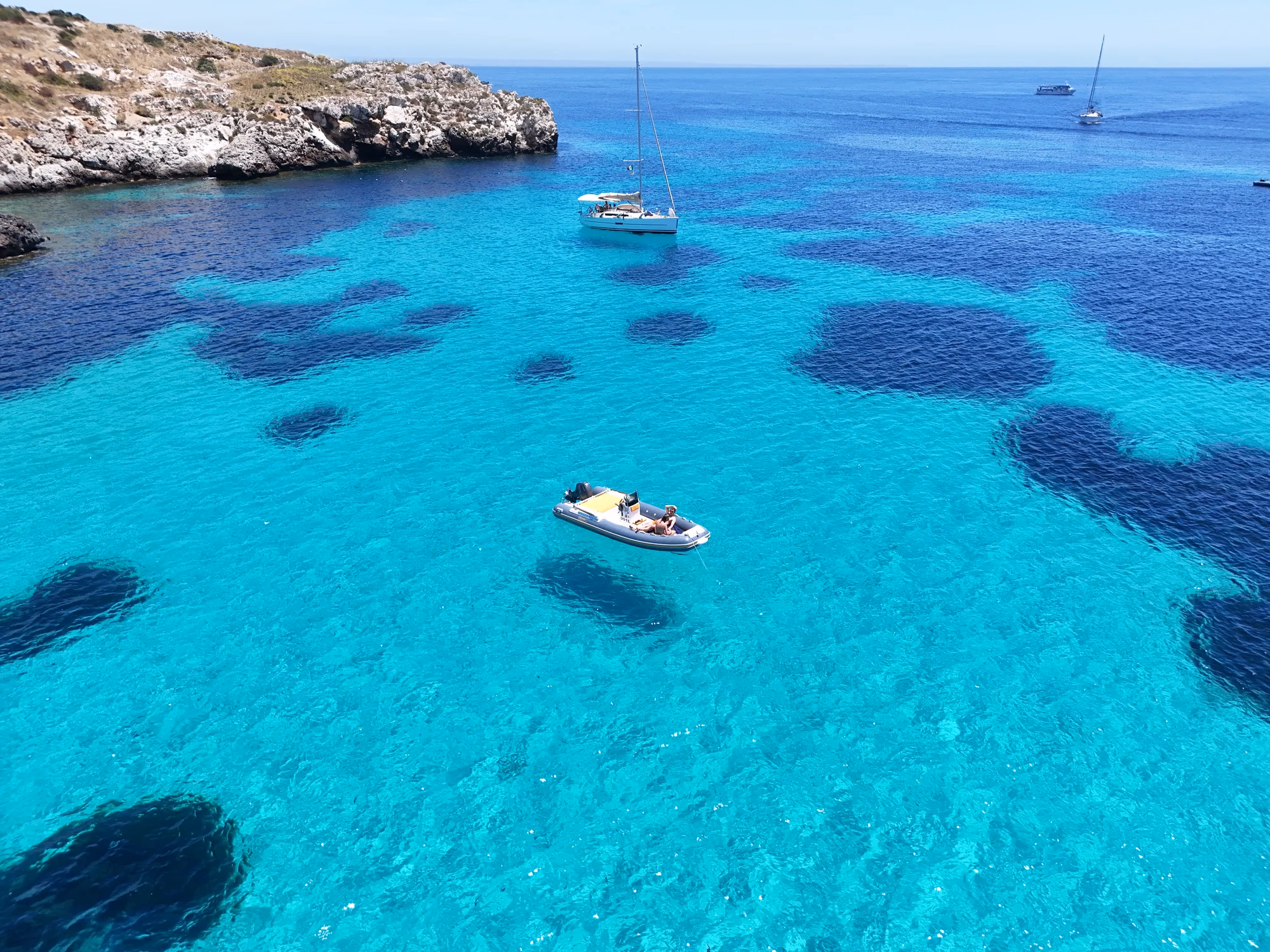 Barca a vela alla fonda su fondali turchesi, a Favignana