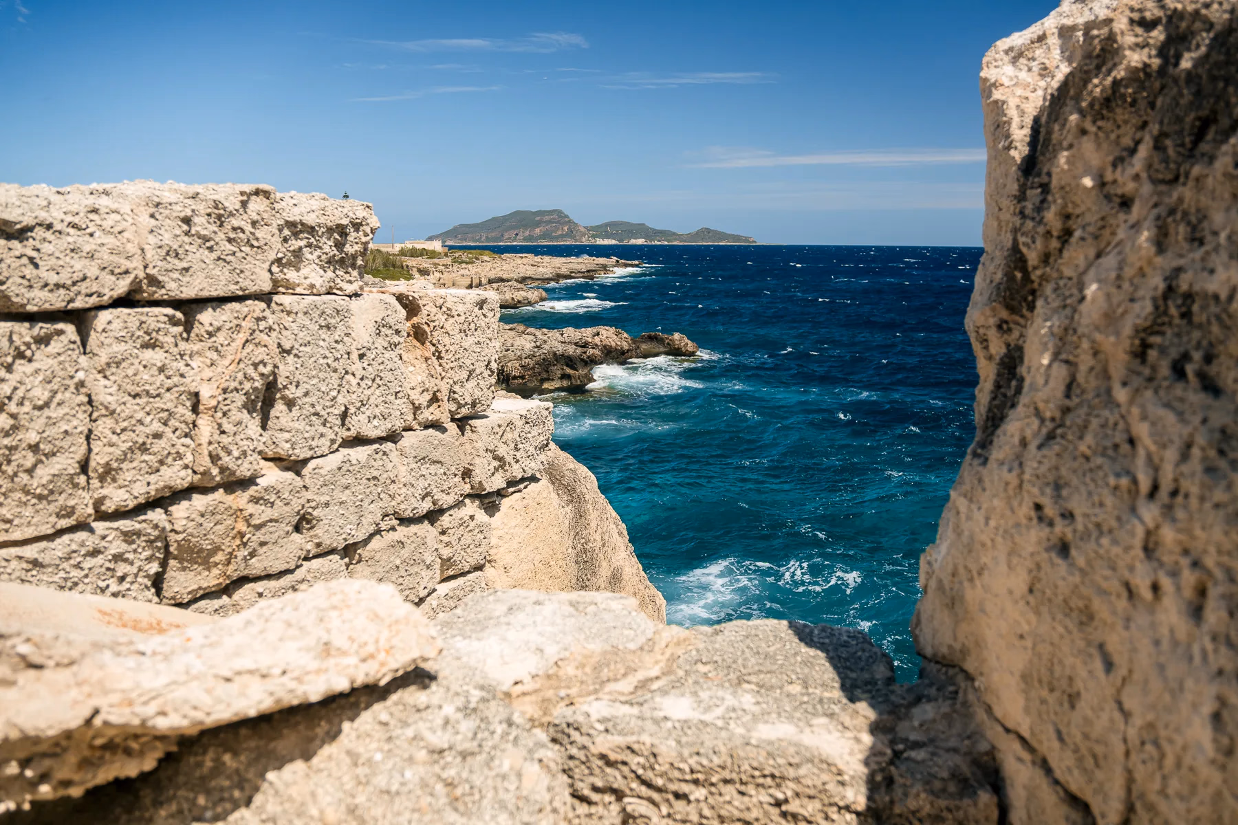 La costa rocciosa di Favignana, con un'isola delle Egadi all'orizzonte
