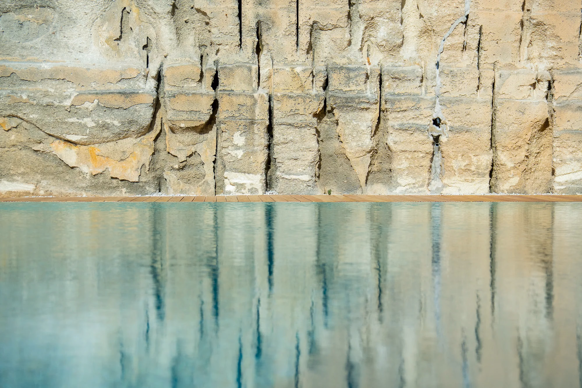 La parete della cava e il suo riflesso nell'acqua ferma, all'ombra