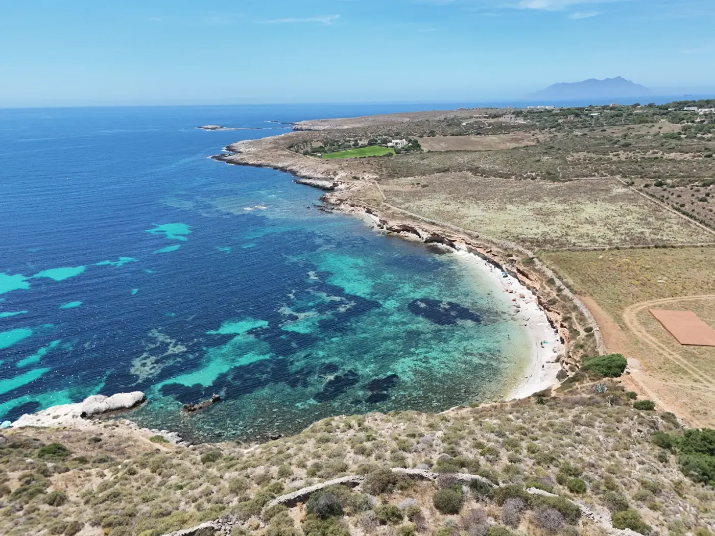 Il profilo della costa di Favignana dall’alto, tra campi, macchia e mare