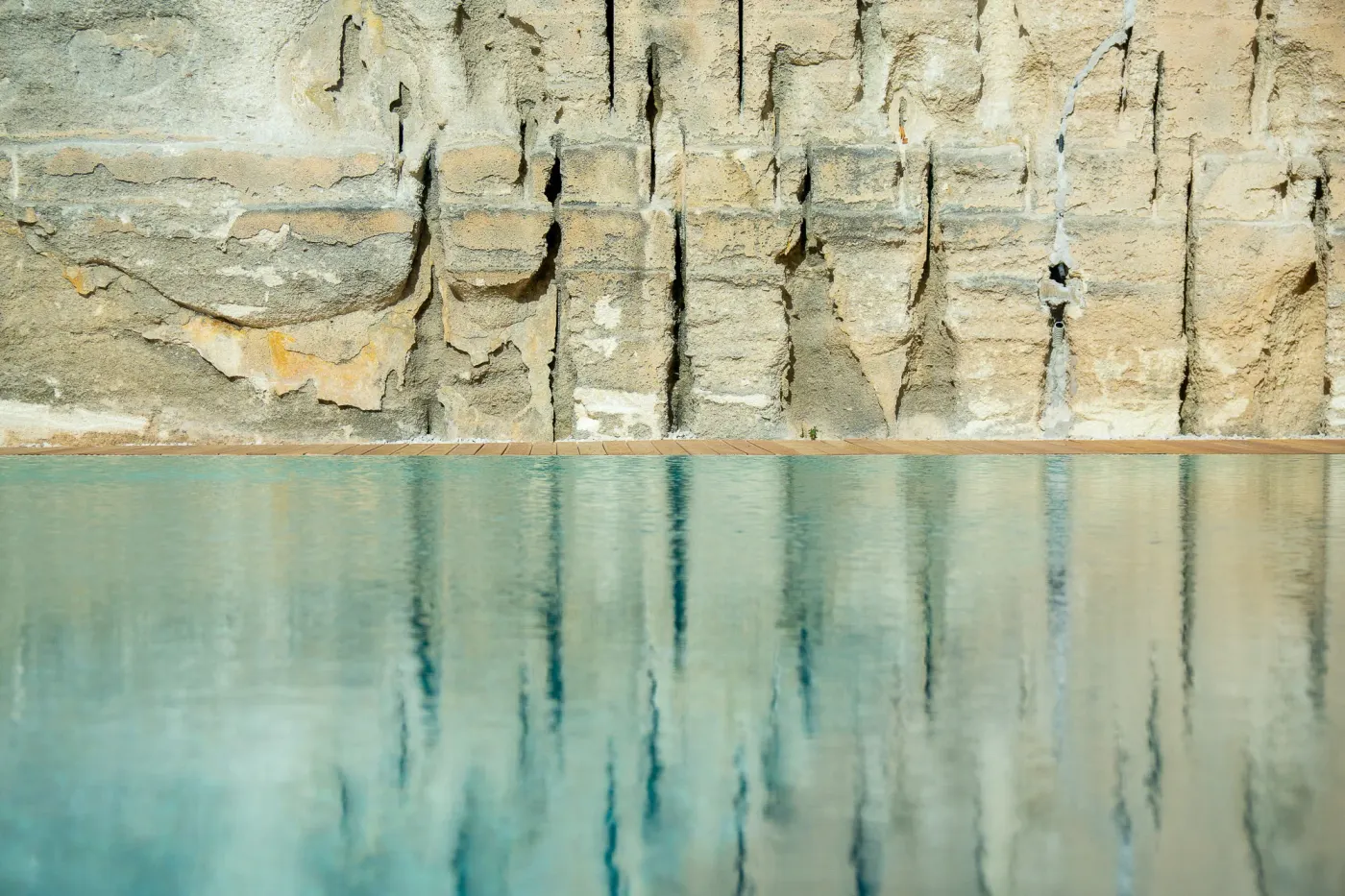 Parete di calcarenite tagliata dai pirreri, riflessa nell’acqua della piscina